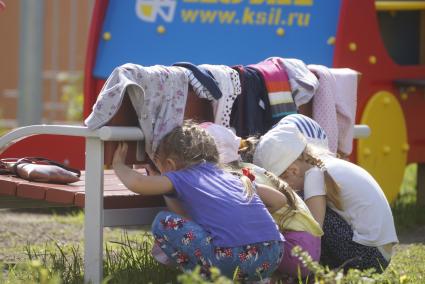 Дети прячутся от воспитателя за скамейкой,во время прогулки на детской площадке детского сада. Екатеринбург