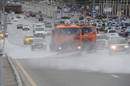 Москва. Поливальные машины моют дорогу  на Крымском мосту.