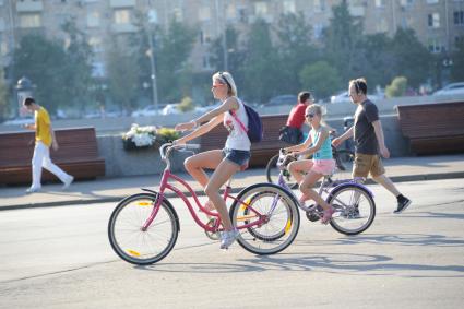 Москва.  Женщина и девочка катаются на велосипедах в Парке Горького.