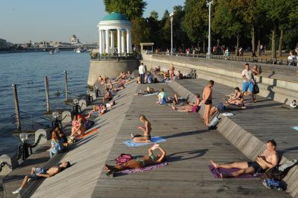 Москва.  Люди загорают на Пушкинской набережной  в Парке Горького.