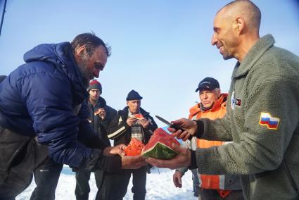 Ничальник станции Дмитрий Мамадалиев (справа) угощает полярников арбузом подаренным корреспондентами Комсомольской правды. Полярники, члены экспедиции сезонной дрейфующей станции \"Северный полюс 2015\" перед эвакуацией на большую землю. Северный полюс. Северный ледовитый океан