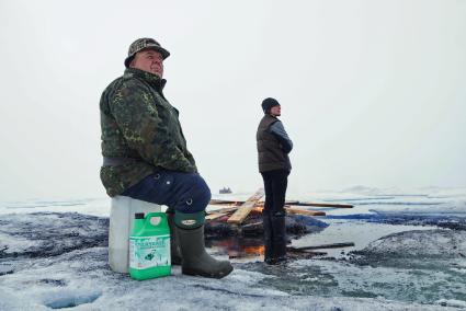 Полярники у костра из остатков стройматериалов и мусора, наблюдают как вертолет Ка-32 МЧС России перевозит аппаратуру и имущество с сезонной дрейфующей станции \"Северный полюс 2015\" из Арктики, на ледокол \"Капитан Драницын\" перед эвакуацией на большую землю. Северный полюс. Северный ледовитый океан