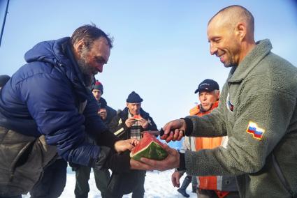 Ничальник станции Дмитрий Мамадалиев (справа) угощает полярников арбузом подаренным корреспондентами Комсомольской правды. Полярники, члены экспедиции сезонной дрейфующей станции \"Северный полюс 2015\" перед эвакуацией на большую землю. Северный полюс. Северный ледовитый океан