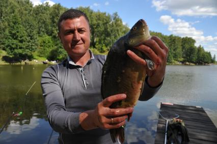 Московская область, д. Мисайлово. Мужчина с зеркальным карпом в руках во время фестиваля семейной рыбалки с радио `Комсомольская правда`, в парке рыбалки и отдыха `Лагуна`.