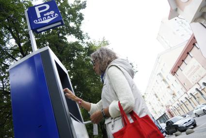 Женщина оплачивает  в паркомате парковку автомобиля