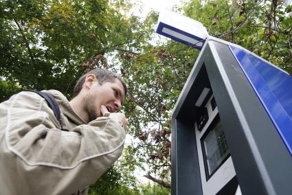 Мужчина оплачивает  в паркомате парковку автомобиля