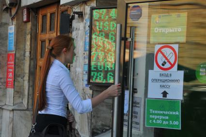 Москва. Девушка входит в операционную кассу обмена валют. Доллар - 67 евро - 77 рублей.