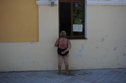 Крым. г. Евпатория. Женщина в купальнике заглядывает в окно дома.