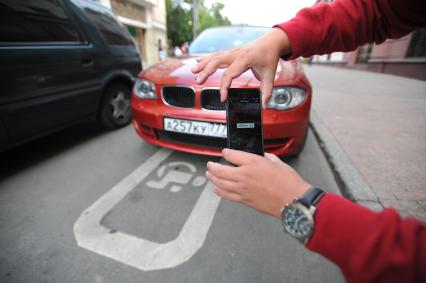 Москва.   Мужчина фиксирует неправильно припаркованный автомобиль с помощью приложения `Помощник Москвы`.