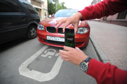 Москва.   Мужчина фиксирует неправильно припаркованный автомобиль с помощью приложения `Помощник Москвы`.