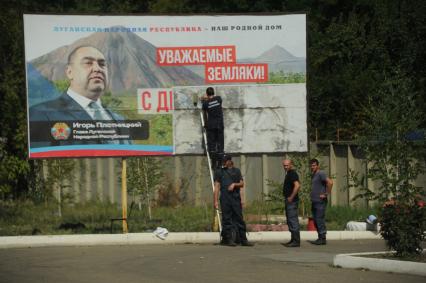 Украина. Луганская область. г.Краснодон. Рабочие клеют на билборд изображение главы ЛНР Игоря Плотницкого, поздравляющего жителей с Днем Шахтера.