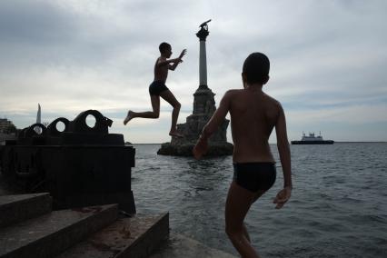 Севастополь. Мальчики прыгают в воду на фоне памятника затопленным кораблям.