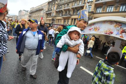 Москва. Мужчина несет ребенка на руках во время празднования Дня города на Тверской улице.