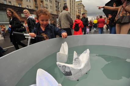 Москва. Девочка запускает бумажные кораблики во время празднования Дня города на Тверской улице.