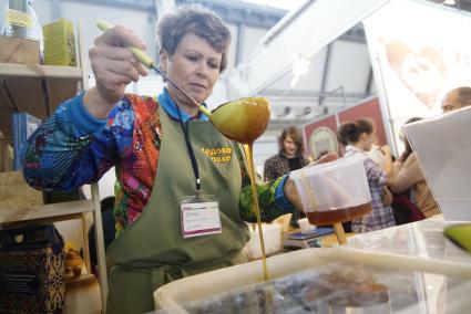 Екатеринбург. 16-ая Агропромышленная выставка. Женщина наливает мед в банку.