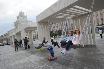 Москва. Девушки качаются на качелях на Триумфальной площади после реконструкции.