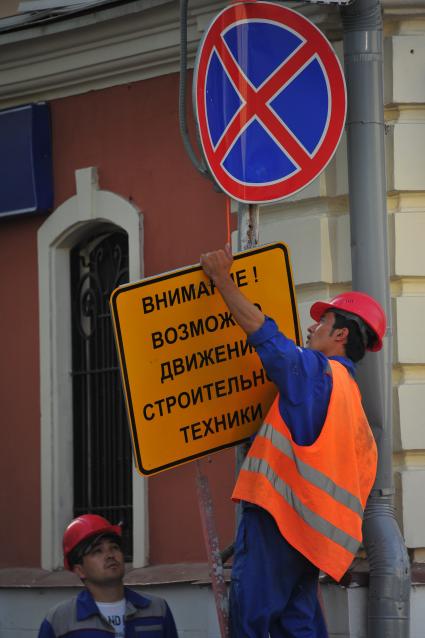 Москва. Мужчина устанавливает табличку на улице Большая Ордынка.