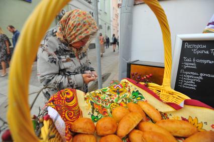 Москва. Пожилая женщина покупает пирожки на улице Большая Ордынка.