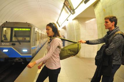 Москва.  Молодой человек тянет девушку за рюкзак  на станции метро `Цветной бульвар`.