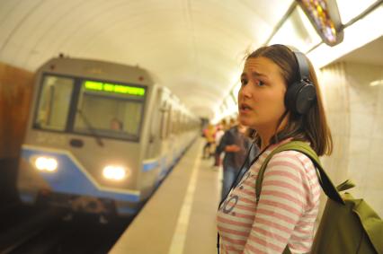 Москва. Девушка в наушниках ждет поезд  на станции метро `Цветной бульвар`.