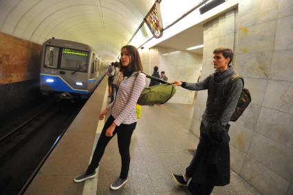 Москва.  Молодой человек тянет девушку за рюкзак  на станции метро `Цветной бульвар`.