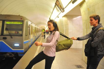 Москва.  Молодой человек тянет девушку за рюкзак  на станции метро `Цветной бульвар`.