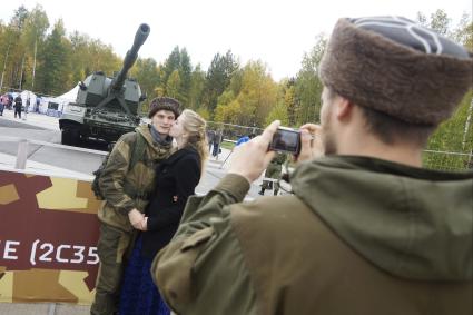 Нижний Тагил. Влюбленная пара фотографируется на фоне самоходной артиллерийской установки `Коалиция-СВ` на 10-ой международной выставке вооружений `Russia Arms Expo - 2015`.