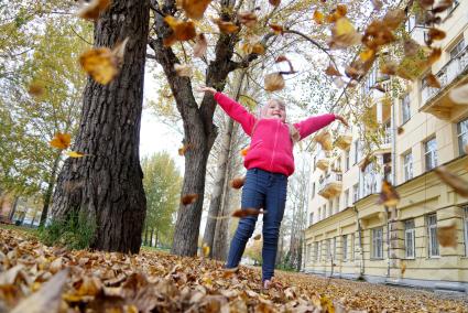 Екатеринбург. Девочка гуляет по парку, усыпанному желтыми опавшими листьями.