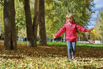 Екатеринбург. Девочка гуляет по парку, усыпанному желтыми опавшими листьями.