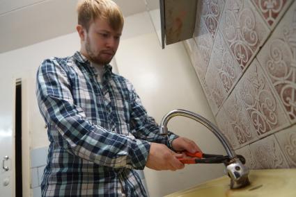 Екатеринбург. Мужчина с разводным ключом пытается отремонтировать водопроводный кран.