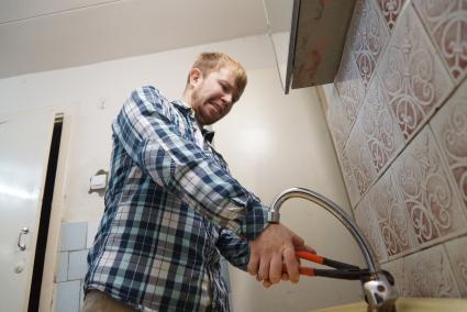 Екатеринбург. Мужчина с разводным ключом пытается отремонтировать водопроводный кран.