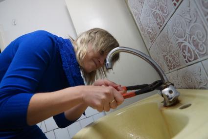 Екатеринбург. Девушка с разводным ключом пытается отремонтировать водопроводный кран.