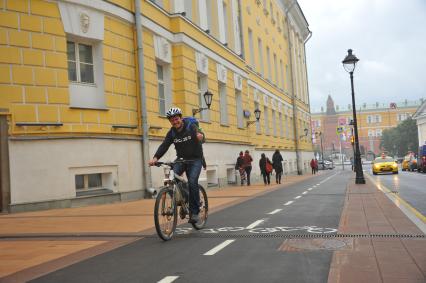 Москва.  Мужчина на велосипеде едет по велодорожке на Большой Никитской улице.