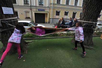 Москва. Девочка качается в гамаке около уличного кафе в Кривоколенном переулке.