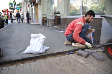 Москва.  Рабочие закатали в асфальт недавно уложенную тротуарную плитку на улице Пречистенка.