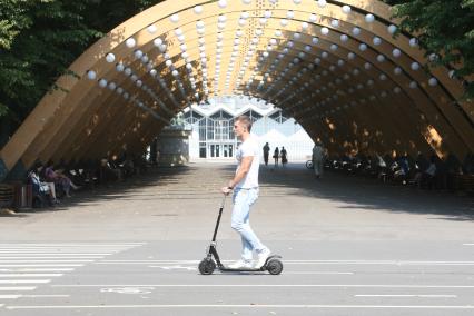 Москва. Мужчина катается на самокате в парке `Сокольники`.