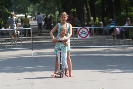 Москва. Девочки катаются на самокате в парке `Сокольники`.