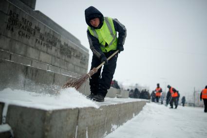 Екатеринбург. Гастарбайтер убирает снег с памятника во время снегопада.