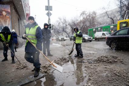 Екатеринбург. Гастарбайтеры убирают лопатами снег с улицы во время снегопада.