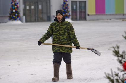 Екатеринбург. Гастарбайтер убирает снег лопатой с улицы.