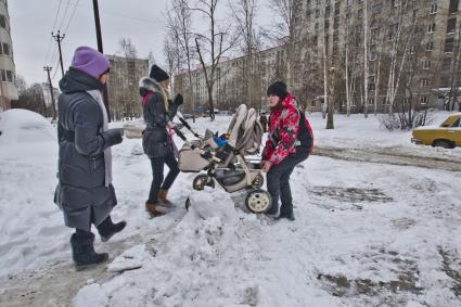Екатеринбург. Женщины переносят детскую коляску через сугробы.