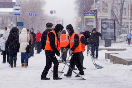 Екатеринбург. Гастарбайтеры убирают снег лопатами во время снегопада.