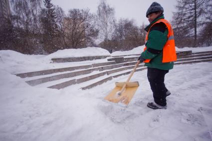 Екатеринбург. Гастарбайтер убирает снег лопатой во время снегопада.