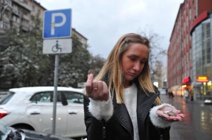 Москва.  Девушка считает деньги на платной автомобильной парковке.