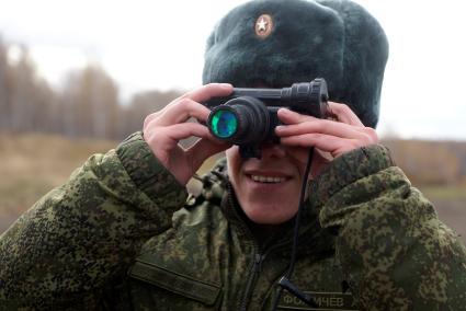 Челябинская область. Чебаркульский военный полигон. Военнослужащий смотрит через прибор ночного видения на покрашеный краской танк, в ходе испытания краски с антиобледенительным, маскировочным и радиодезактивирующим свойствами.