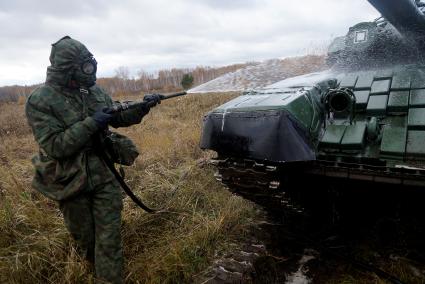 Челябинская область. Чебаркульский военный полигон. Военнослужащий проводит противорадиационную обработку танка Т-72, в ходе испытания краски с антиобледенительным, маскировочным и радиодезактивирующим свойствами.