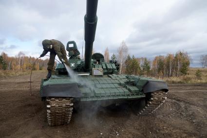 Челябинская область. Чебаркульский военный полигон. Военнослужащий поливает растворителем танк Т-72 в ходе испытания краски с антиобледенительным, маскировочным и радиодезактивирующим свойствами.