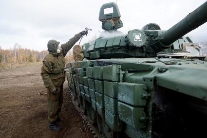 Челябинская область. Чебаркульский военный полигон. Военнослужащий поливает растворителем танк Т-72 в ходе испытания краски с антиобледенительным, маскировочным и радиодезактивирующим свойствами.