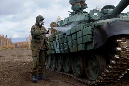 Челябинская область. Чебаркульский военный полигон. Военнослужащий поливает растворителем танк Т-72 в ходе испытания краски с антиобледенительным, маскировочным и радиодезактивирующим свойствами.