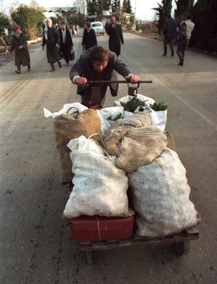 Российско-абхазская граница. 1990-ые. Мужчина везет на тележке мандарины для продажи в России.